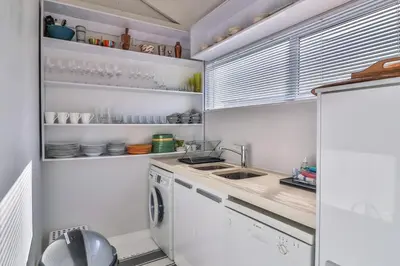 a white kitchen with a sink and a dishwasher at Nordic Family Beach House in Bettyʼs Bay