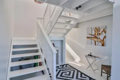 a white staircase in a white room with a table at Nordic Family Beach House in Bettyʼs Bay