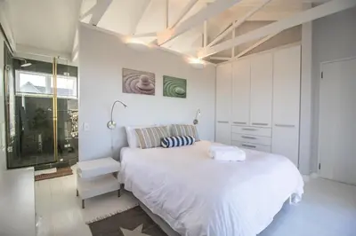 a white bedroom with a large bed and a window at Nordic Family Beach House in Bettyʼs Bay