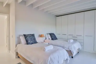 two beds in a room with white walls at Nordic Family Beach House in Bettyʼs Bay
