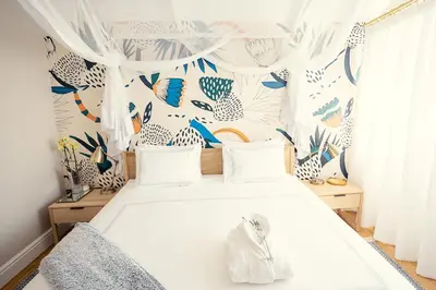 a bedroom with a white bed with blue and white curtains at Roubaix House - A Heritage Retreat in the Heart of Franschhoek in Franschhoek