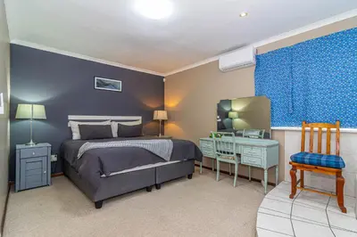 a bedroom with a bed and a desk and a chair at Four Pines in Hermanus