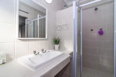 a white bathroom with a sink and a shower at Four Pines in Hermanus