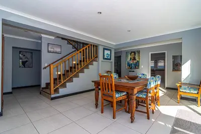 a dining room with a table and chairs and a staircase at Four Pines in Hermanus