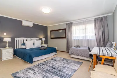 a bedroom with two beds and a table and a couch at Four Pines in Hermanus