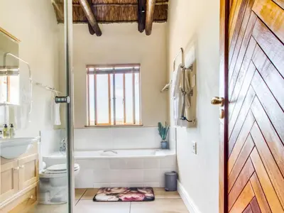 a bathroom with a tub and a toilet and a door at Blue Crane House