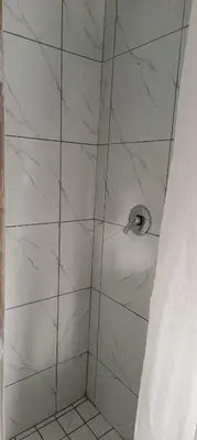 a shower with white marble walls and a shower head at PEACEFUL SLEEP lodge in Goodwood