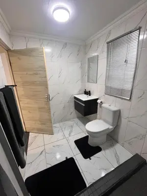 a white bathroom with a toilet and a sink at Casa Bracken in Windsor Park