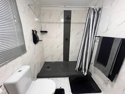 a white bathroom with a shower and a toilet at Casa Bracken in Windsor Park
