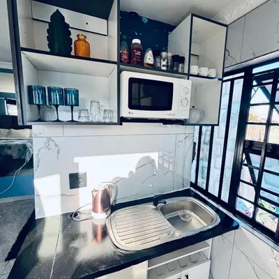 a kitchen with a sink and a microwave at Browns villa and construction pty ltd in Cape Town