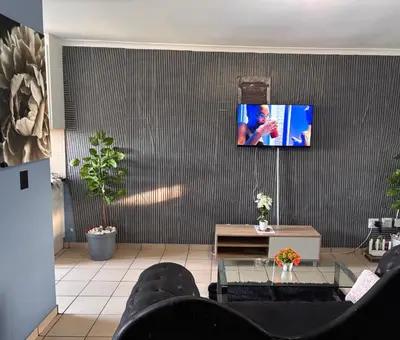 a living room with a couch and a tv on a wall at Browns villa and construction pty ltd in Cape Town