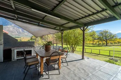 a patio with a table and chairs and a fireplace at Grietjiesdrif- Mountain Retreat in Rawsonville
