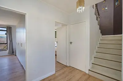 a hallway with white walls and stairs in a house at 8 Sleeper Luxury Duplex Penthouse in Cape Town