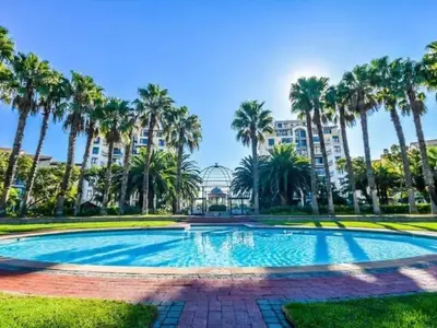 a large swimming pool with palm trees and a building at 8 Sleeper Luxury Duplex Penthouse in Cape Town