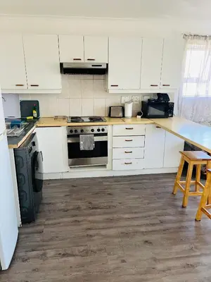 a kitchen with white cabinets and a stove at 2 bedroom flat in Pinelands near Old Mutual in Cape Town