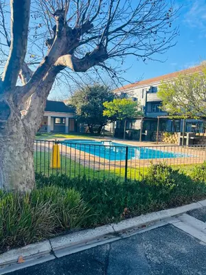a fence with a pool in front of a building at 2 bedroom flat in Pinelands near Old Mutual in Cape Town