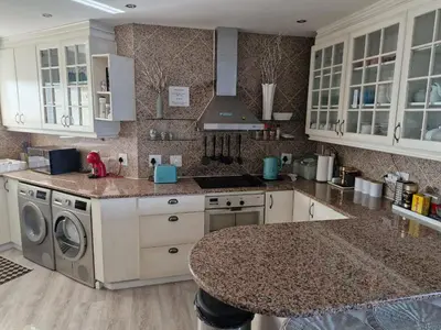 a kitchen with white cabinets and a marble counter top at PENTHOUSE Luxury Apartment Amazing Sea Views CAPE TOWN in Strand