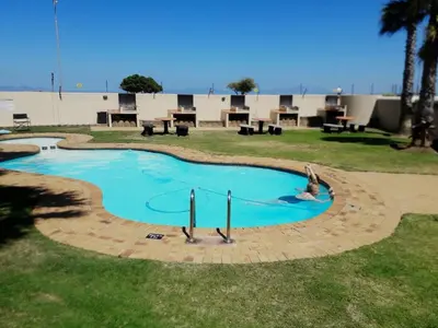 a woman is in a swimming pool in a park at PENTHOUSE Luxury Apartment Amazing Sea Views CAPE TOWN in Strand