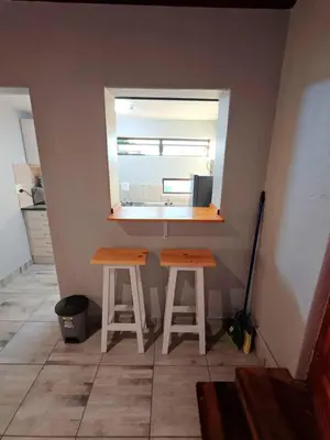 a small kitchen with two stools and a window at Sunbird Studio Apartment in Brackenfell
