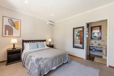 a bedroom with a large bed and a bathroom at Tambula Guest House in Cape Town