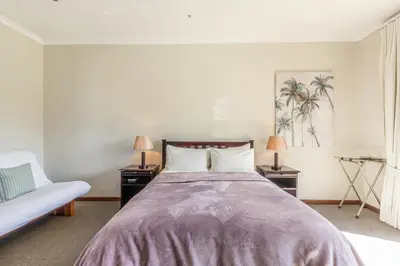 a bedroom with a large bed with two tables and a couch at Tambula Guest House in Cape Town