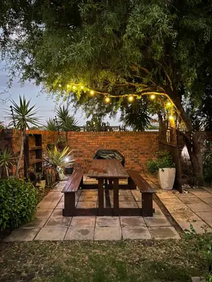 a wooden picnic table under a tree with lights at Tambula Guest House in Cape Town