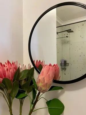 a vase with pink flowers in front of a mirror at Studio Apartment 100 meters to Strand Beach in Strand