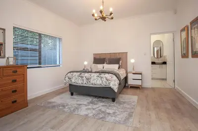 a bedroom with a bed and a dresser and a window at Tree Fern Cottage in Hermanus