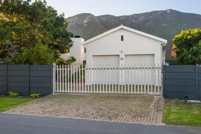 a white house with a white picket fence at Tree Fern Cottage in Hermanus