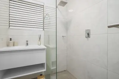 a white bathroom with a shower and a sink at Searenity Tides in Cape Town