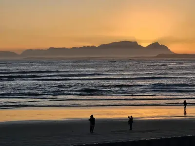 three people standing on the beach at sunset at Searenity Tides in Cape Town
