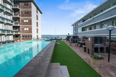 a swimming pool in front of a building at Searenity Tides in Cape Town