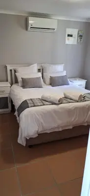 a bedroom with a large bed with white sheets and pillows at Firehouse selfcatering Garden Cottages no 5 in Wellington