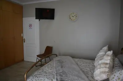a bedroom with a bed and a clock on the wall at Pualani Self Catering in Strand
