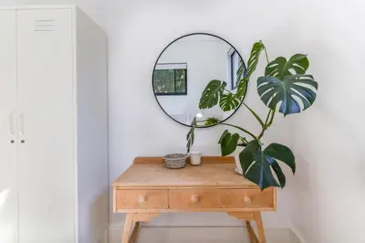 a mirror on top of a wooden table with a plant at Contemporary Apartment With Shared Swimming Pool in Stellenbosch