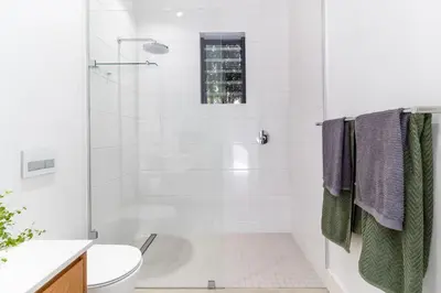 a white bathroom with a shower and a toilet at Contemporary Apartment With Shared Swimming Pool in Stellenbosch
