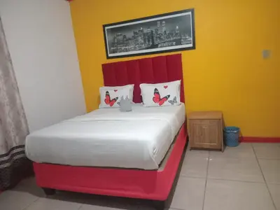 a bed with a red headboard in a room at Neo & Ruks Guest house parow 1 in Avondale