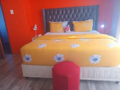 a bedroom with a large yellow bed with a red chair at Neo & Ruks Guest house parow 1 in Avondale