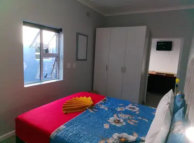 a bedroom with a bed with a red blanket and a window at Neo & Ruks Guest house parow 1 in Avondale