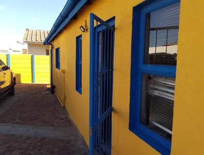 a yellow and blue building with a blue door at Neo & Ruks Goodwood 1 in Goodwood