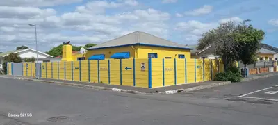 a yellow building with a fence next to a street at Neo & Ruks Goodwood 1 in Goodwood
