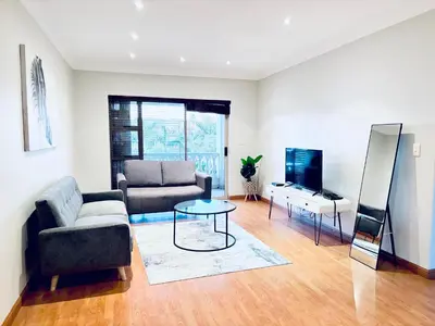 a living room with a couch and a table at Spanish Charm in the Heart of Century City Stylish Stay Near Canal Walk! in Cape Town
