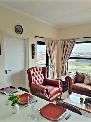 a living room with two chairs and a table at Blouberg Luxury Oasis With Pool & Scenic Mountain Views in Cape Town