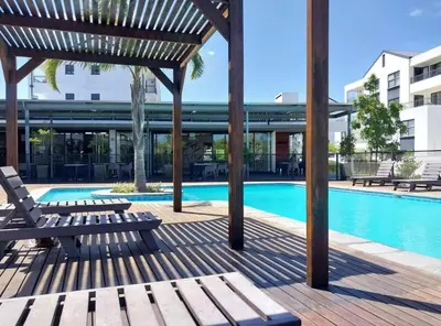 a swimming pool with benches next to a building at Blouberg Luxury Oasis With Pool & Scenic Mountain Views in Cape Town