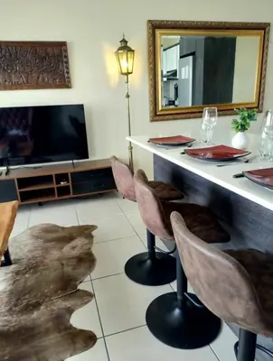 a living room with a table with chairs and a mirror at Blouberg Luxury Oasis With Pool & Scenic Mountain Views in Cape Town