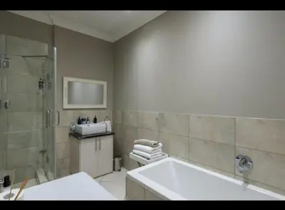 a bathroom with a tub and a shower and a sink at Merweda Wag-n-Bietjie on Dorp Street in Stellenbosch