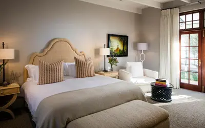 a bedroom with a large bed and a chair at Leeu Estates in Franschhoek