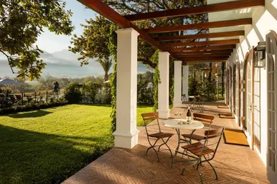 a patio with a table and chairs on a lawn at Leeu Estates in Franschhoek