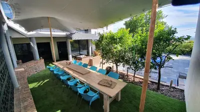 a large wooden table with chairs and an umbrella at Somerset Breeze