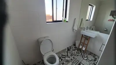 a white bathroom with a toilet and a sink at Somerset Breeze